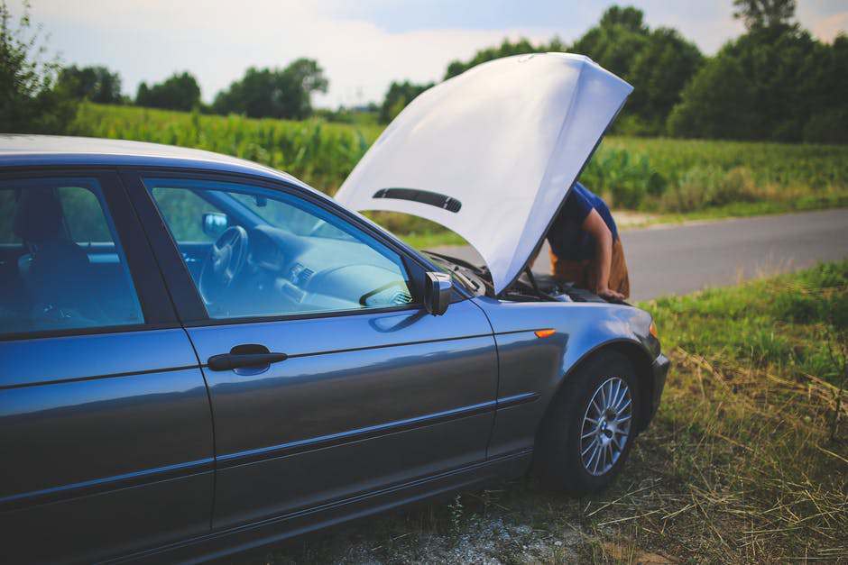  A man examines his car after it breaks down on the side of the road.