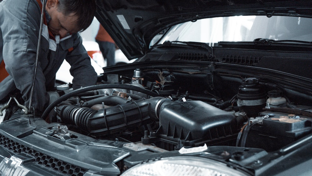 A technician working on the engine bay of a vehicle.